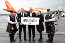 Image of cabin crew, bag pipers and captain holding easyJet to Edinburgh prop, standing in front of an easyJet plane