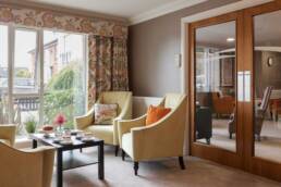 Image inside Oakmont Lodge featuring yellow chairs and a table setup with cups and saucers and cake